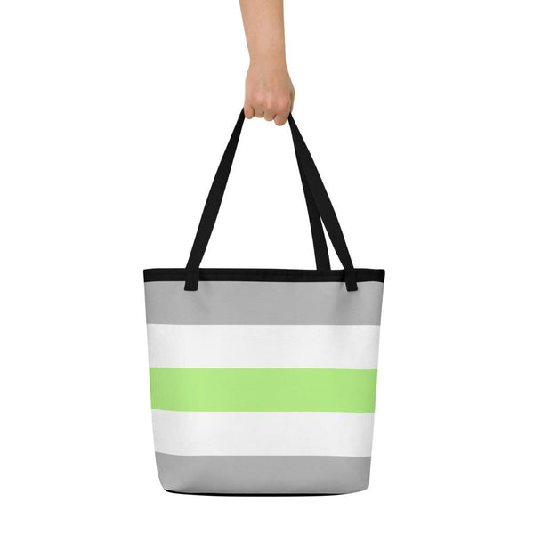 Black-handled tote bag with gray, white, and lime-green horizontal stripes, held up by a hand