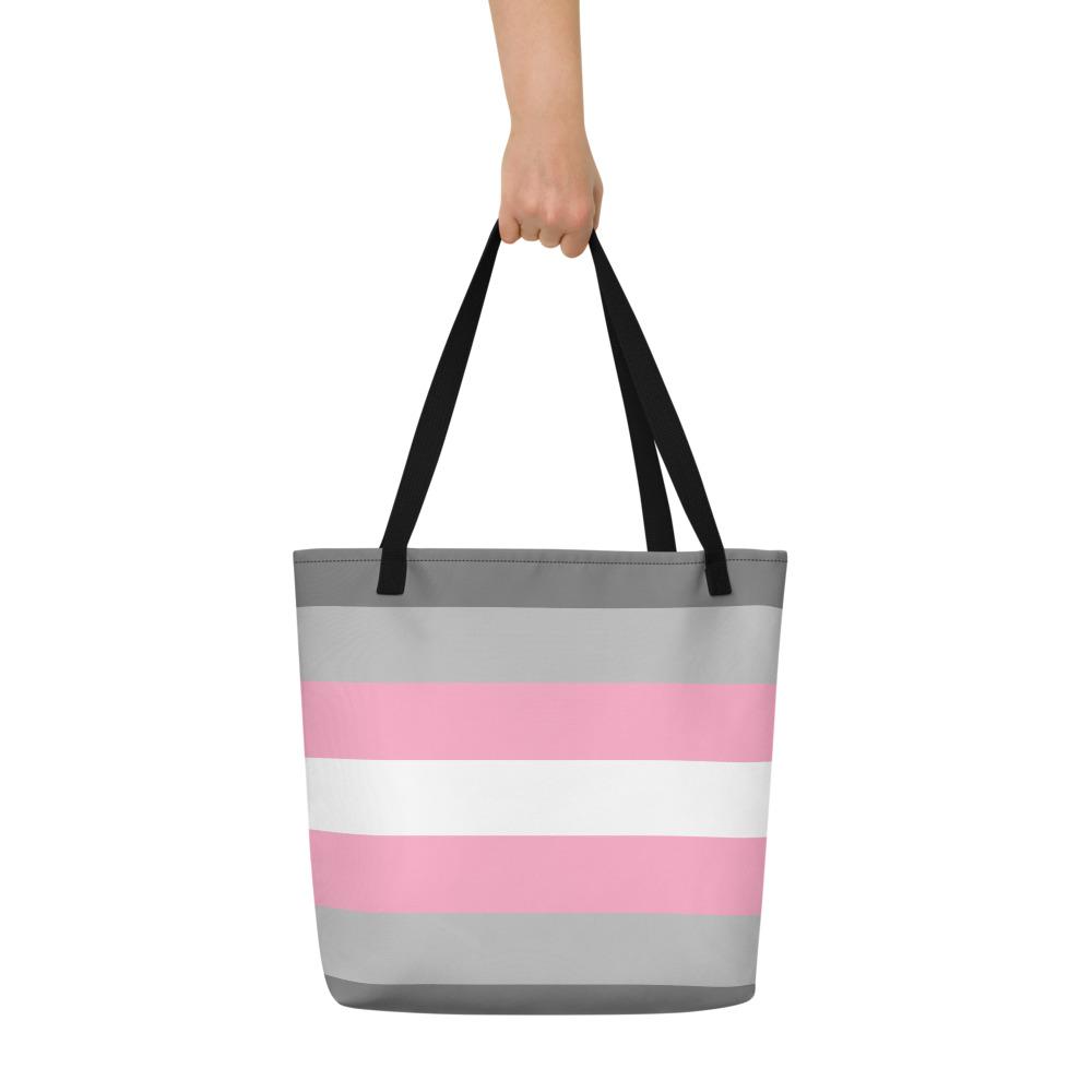 Gray, pink, and white striped tote bag held by one hand against a white background