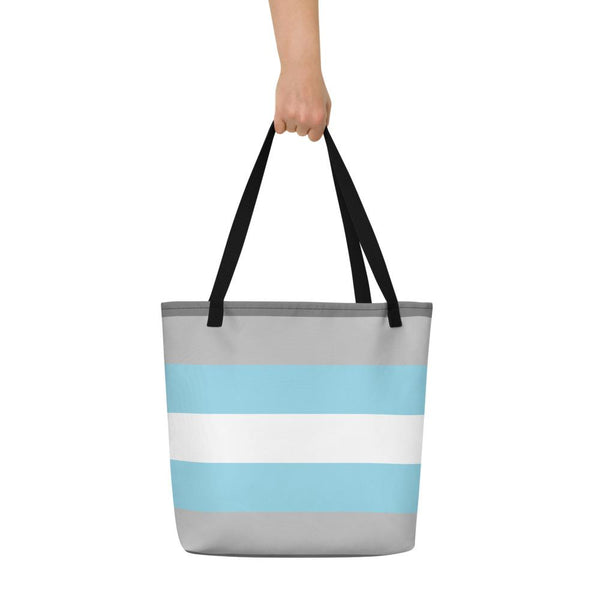 Gray tote bag with light blue and white horizontal stripes, held by one hand