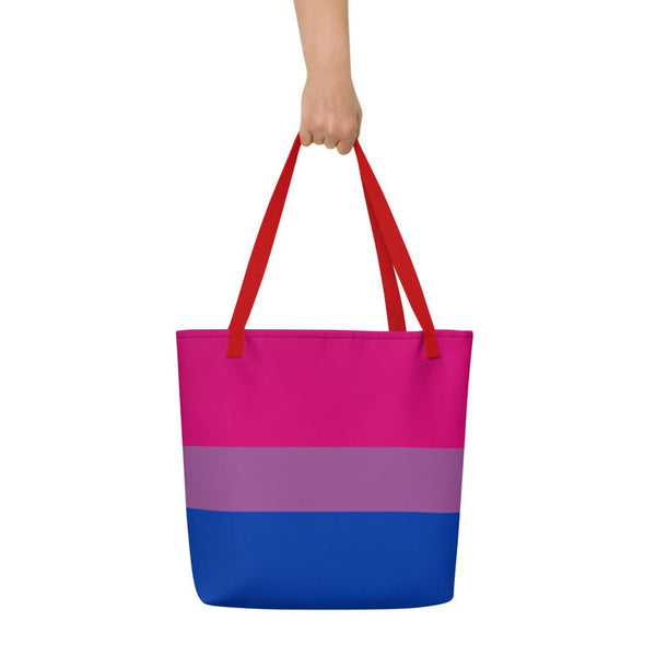 Front view of a large pink, lavender, and blue striped tote bag held by one hand