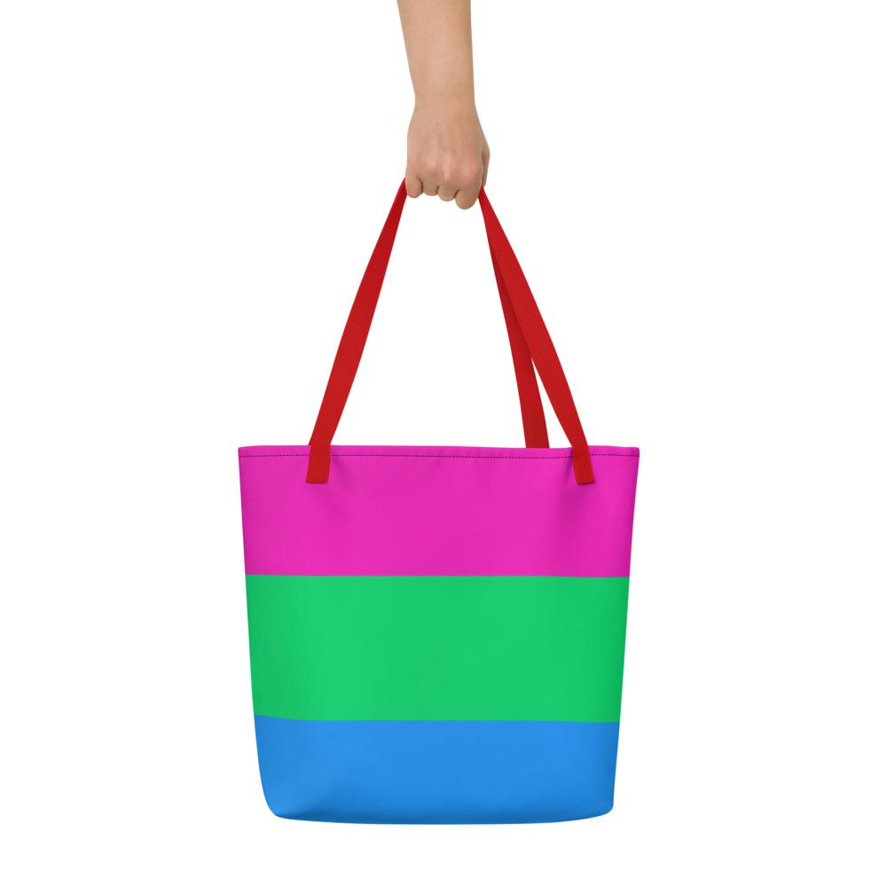Front view of a color-block tote bag with pink, green, and blue panels and red handles