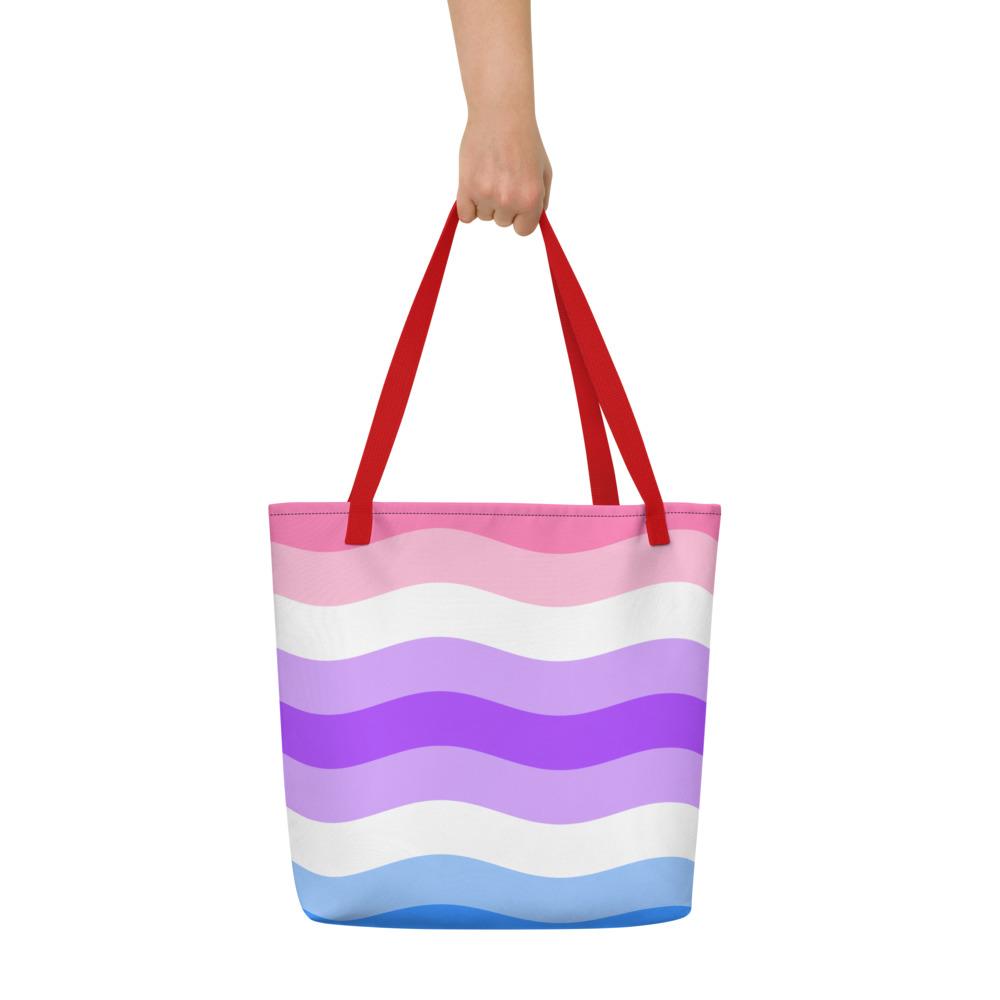 Wavy pink, white, purple, and blue striped tote bag held by one hand
