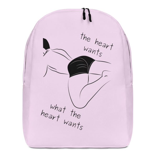 Front view of a pale pink backpack with a black abstract figure and “the heart wants what the heart wants”