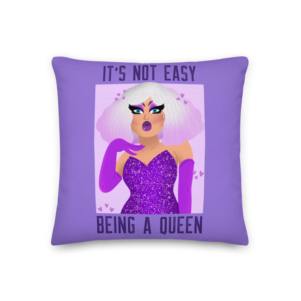 Purple square pillow reading “IT’S NOT EASY BEING A QUEEN” with a glamorous drag queen illustration