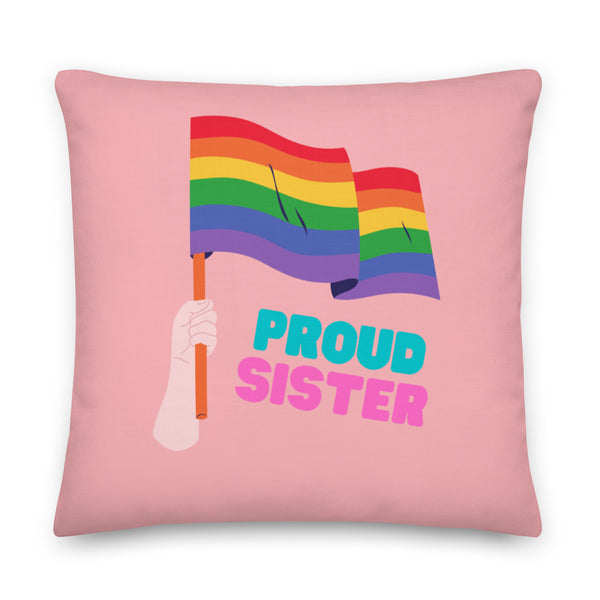 Pink square pillow with a rainbow flag, hand, and the words “PROUD SISTER”