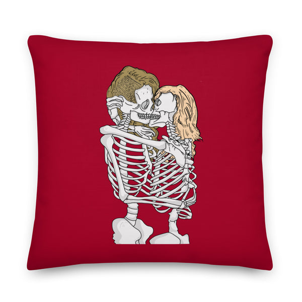 Deep red square pillow featuring two embracing skeletons kissing