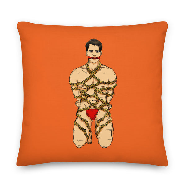 Orange square pillow featuring an illustrated man bound in decorative rope and wearing red underwear