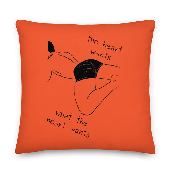 Orange square pillow with a black reclining figure and the words “the heart wants what the heart wants”