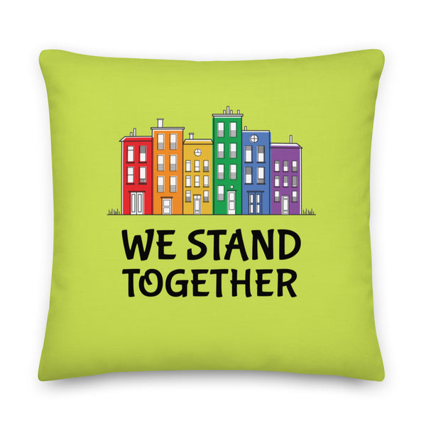 Lime-green square pillow with colorful row houses and the words “WE STAND TOGETHER”