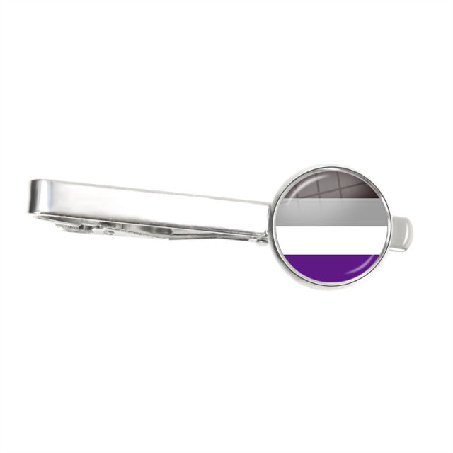 Silver tie clip with a round asexual pride flag face, shown horizontally