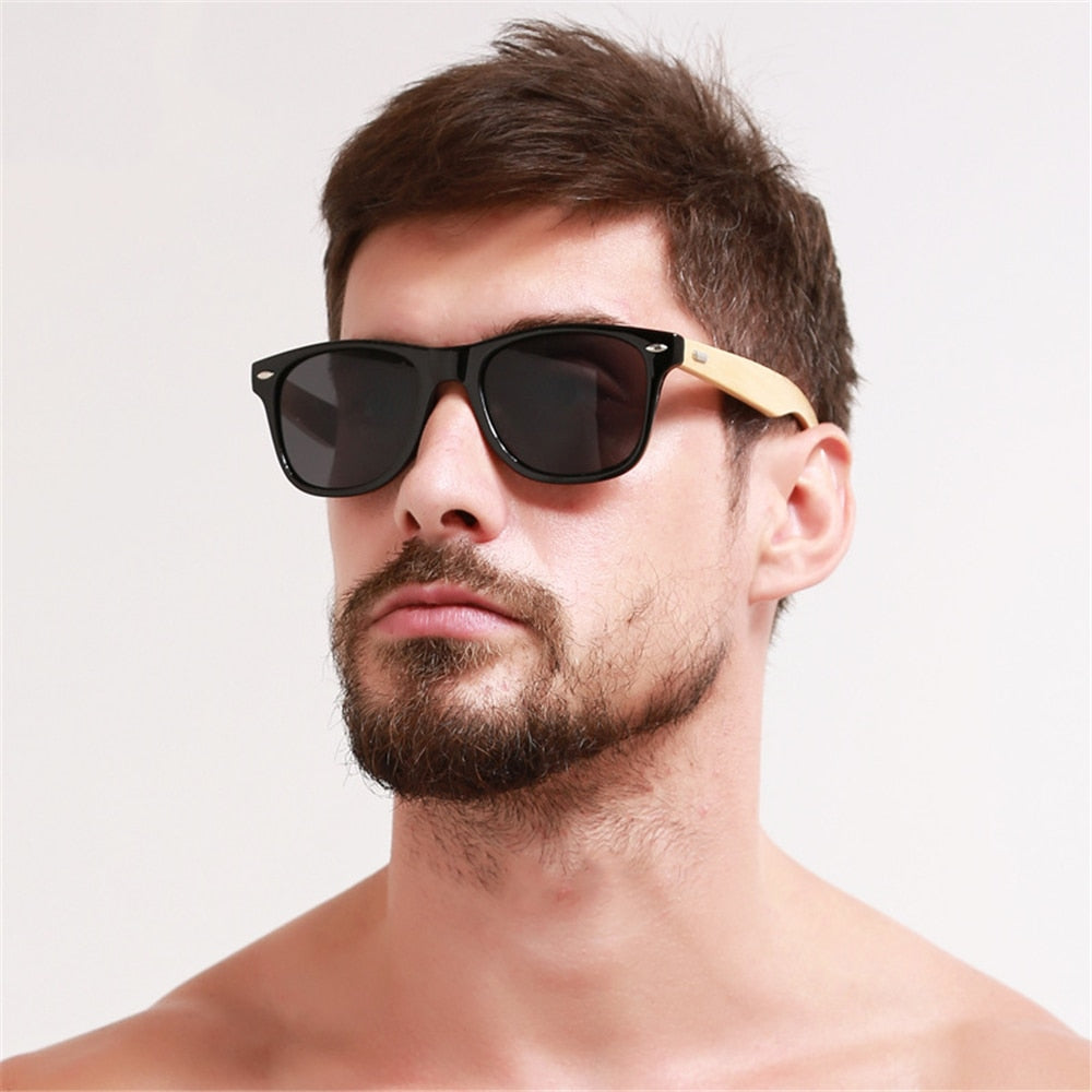 Close-up model wearing black sunglasses with light bamboo-colored arms
