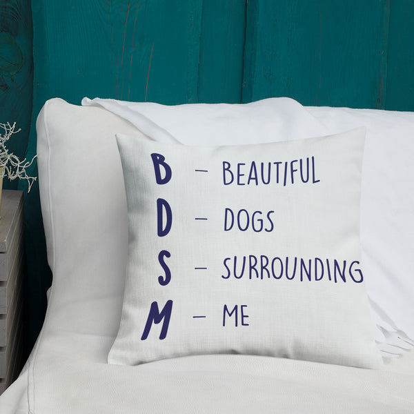 White pillow reading “BDSM — BEAUTIFUL DOGS SURROUNDING ME” on a white bed