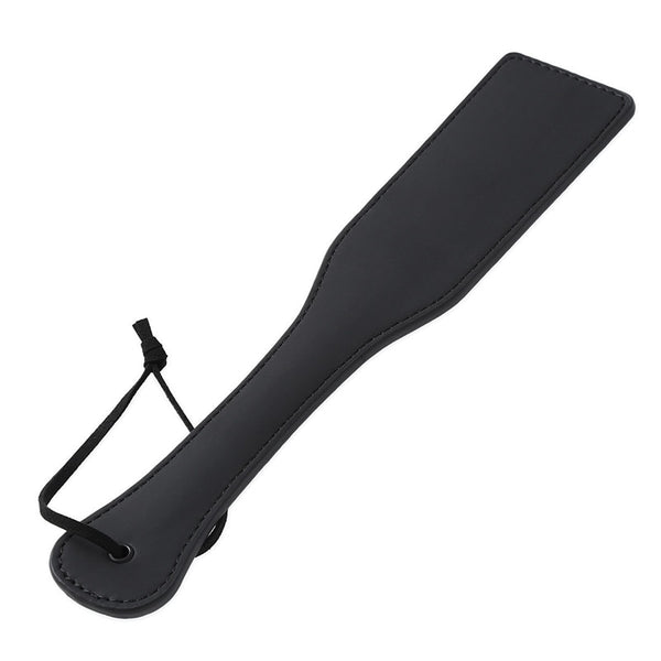 Black leather spanking paddle with a wrist loop, shown diagonally on white