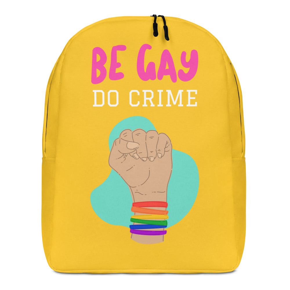 Front view of a yellow backpack reading “BE GAY DO CRIME” above a raised fist with rainbow bands