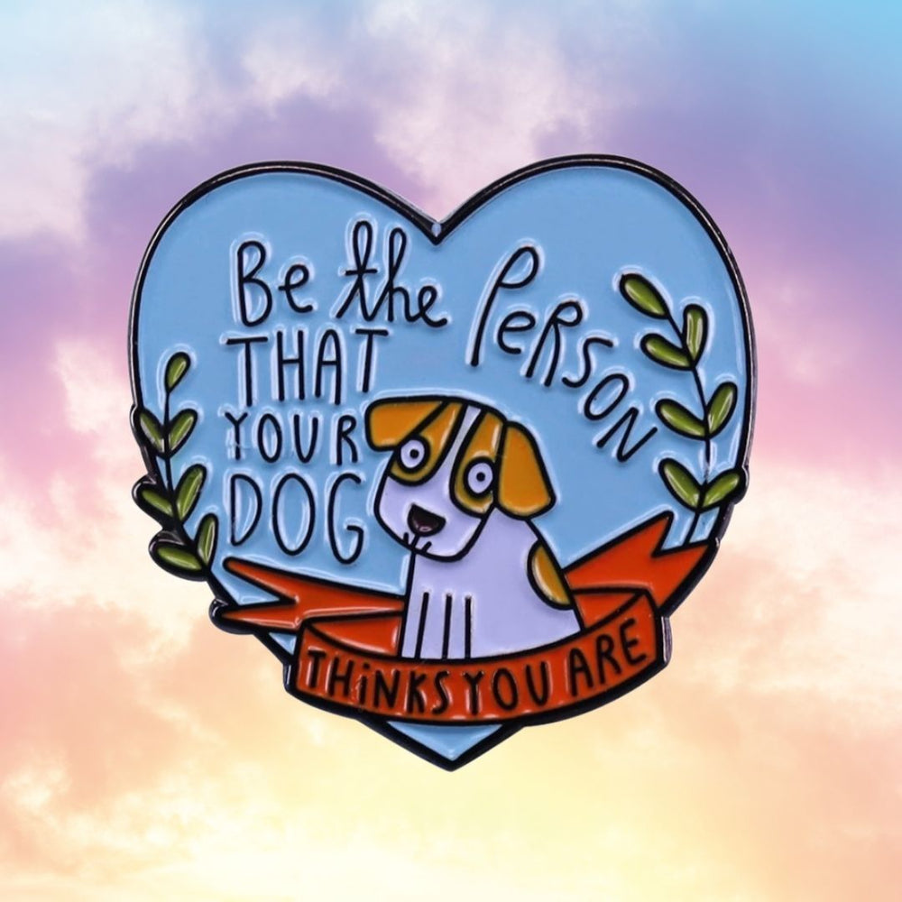 Heart-shaped enamel pin reading “Be the person that your dog thinks you are” with a dog illustration