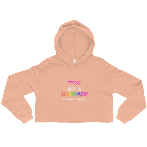 Peach cropped hoodie laid flat, with hearts and rainbow “BE A RAINBOW” chest text