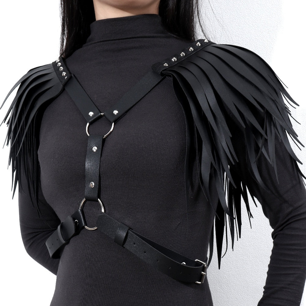 Front view of a person wearing a black faux-leather harness with studded straps and wing-like fringe