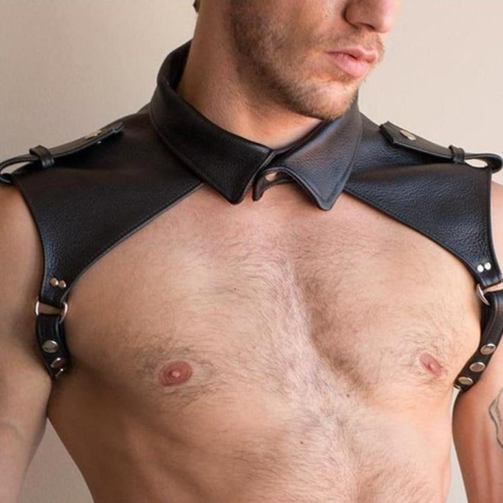 Close-up of a model wearing a black leather-look shoulder harness with collar, rings and snap hardware