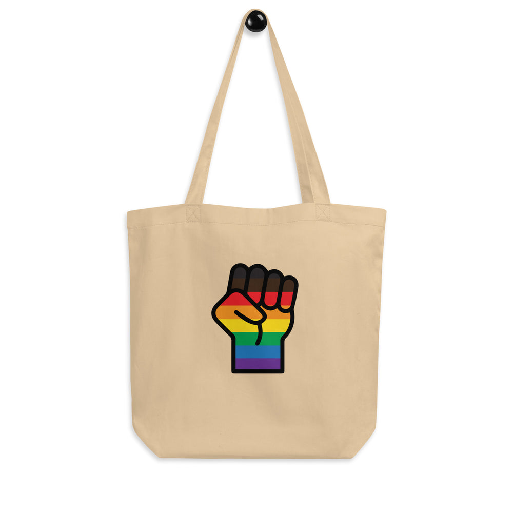 Natural canvas tote bag with long handles and a raised fist in rainbow stripes