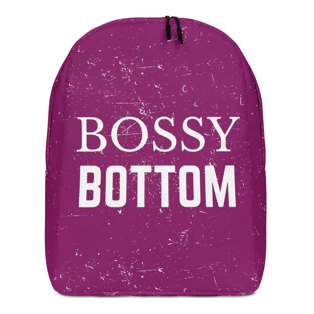 Front view of a magenta backpack with white speckle marks and “BOSSY BOTTOM” lettering