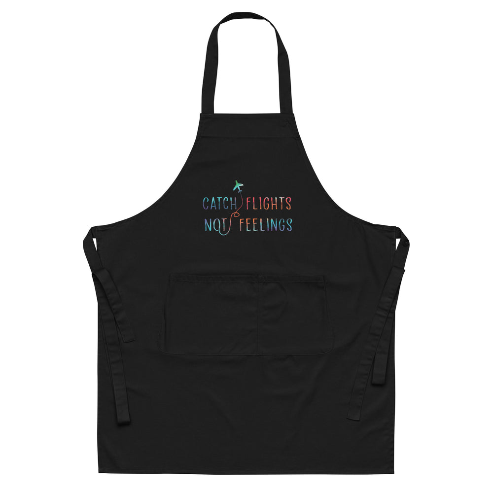Front view of a black apron with colorful “CATCH FLIGHTS NOT FEELINGS” text and a front pocket
