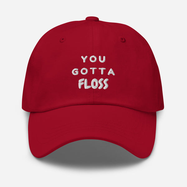 Front view of a red baseball cap embroidered with “YOU GOTTA FLOSS.”