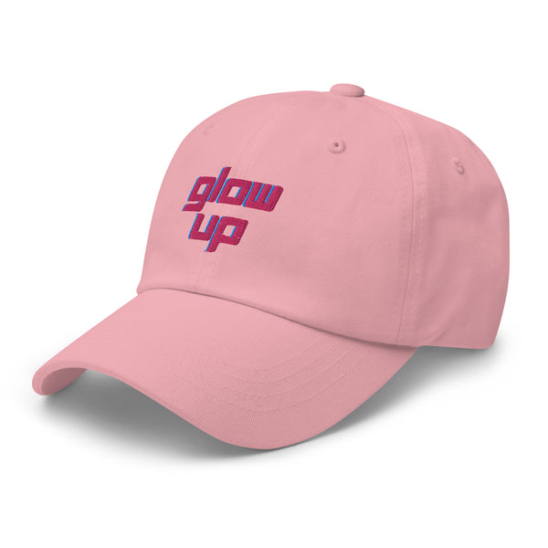 Pink baseball cap shown at an angle with embroidered “glow up” lettering in pink and blue