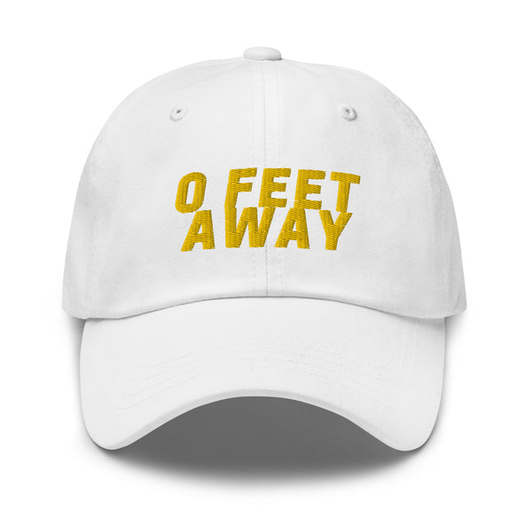 Front view of a white cap embroidered with yellow text reading “0 FEET AWAY”