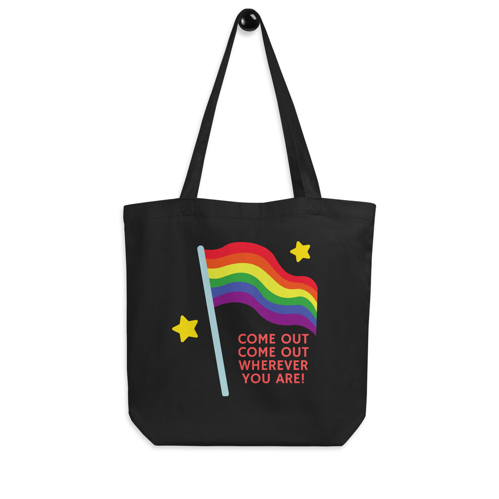 Front view of a black tote bag with a rainbow flag, yellow stars, and “COME OUT COME OUT WHEREVER YOU ARE!”