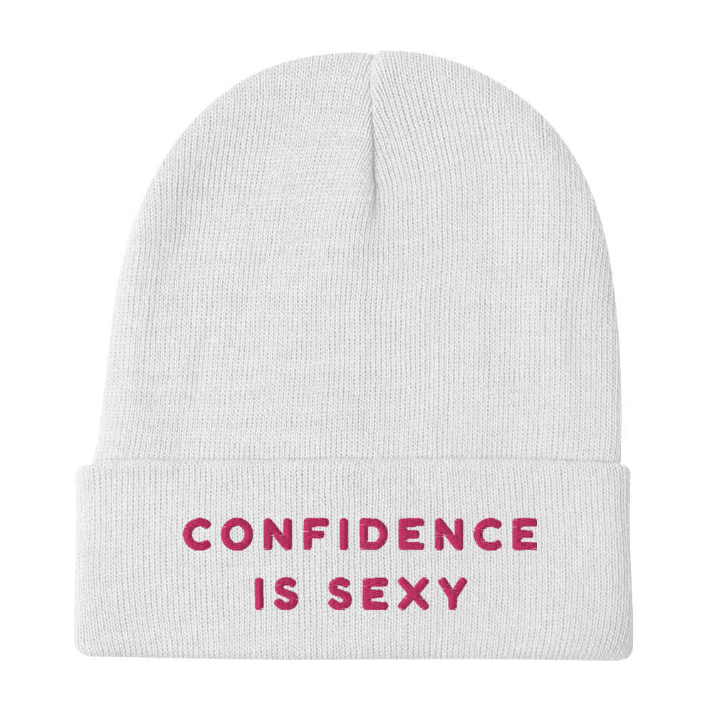 White knit beanie with pink embroidered text reading “CONFIDENCE IS SEXY”
