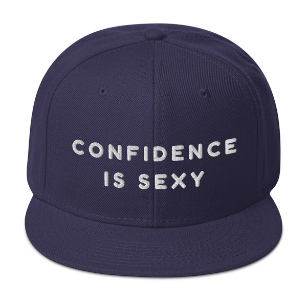 Navy snapback hat with white embroidered text reading “CONFIDENCE IS SEXY”