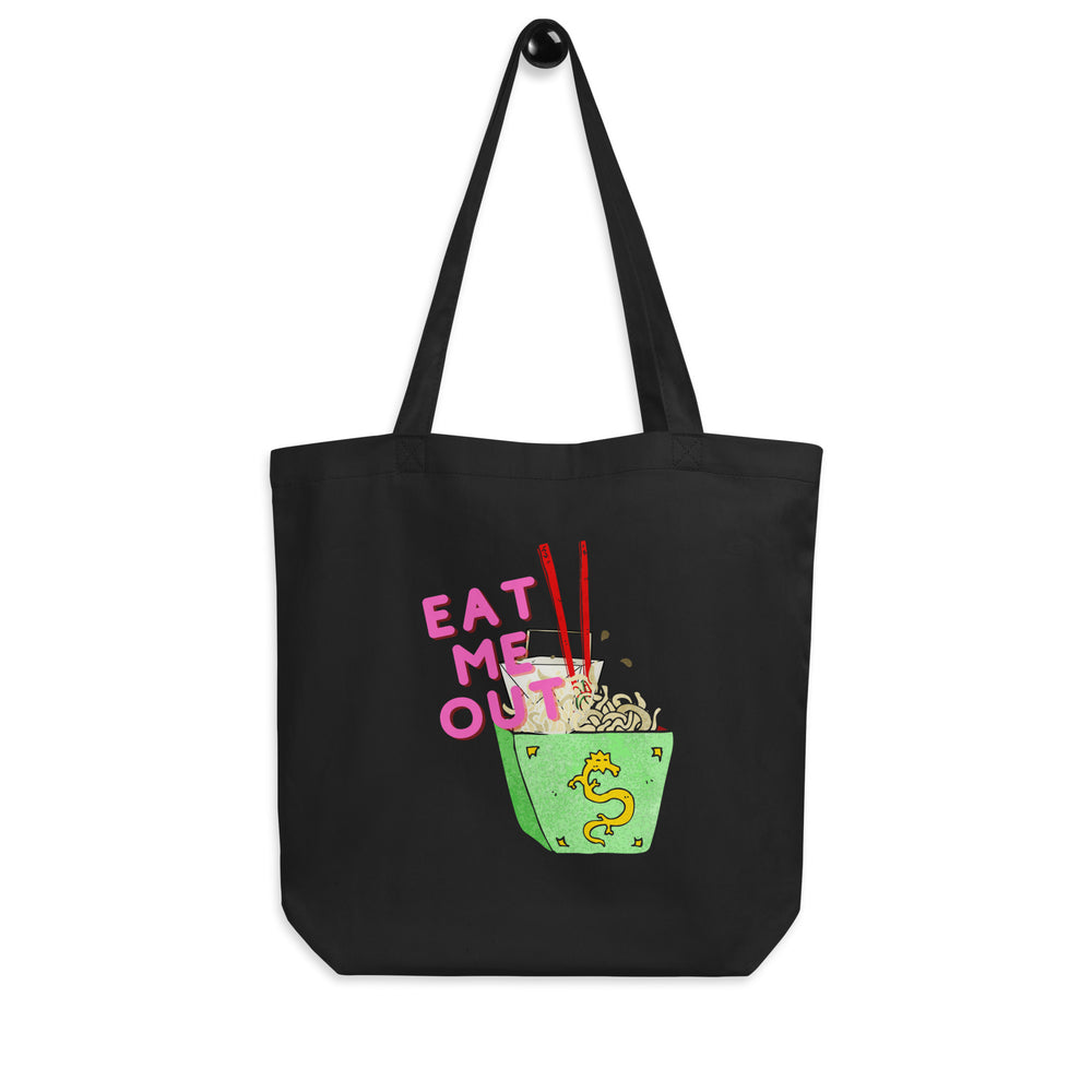 Front view of a black tote bag reading “EAT ME OUT” beside a cartoon noodle bowl