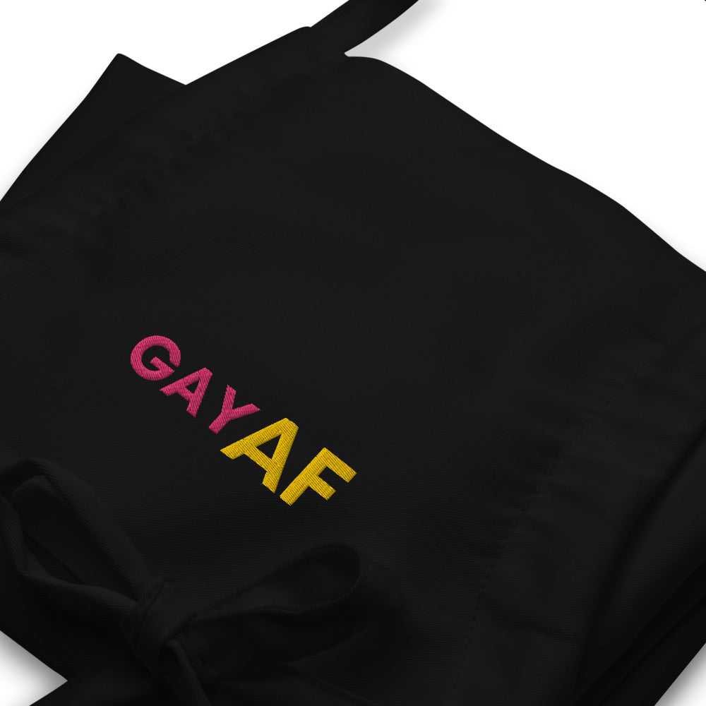 Close-up of a black apron with colorful embroidered “GAY AF” lettering