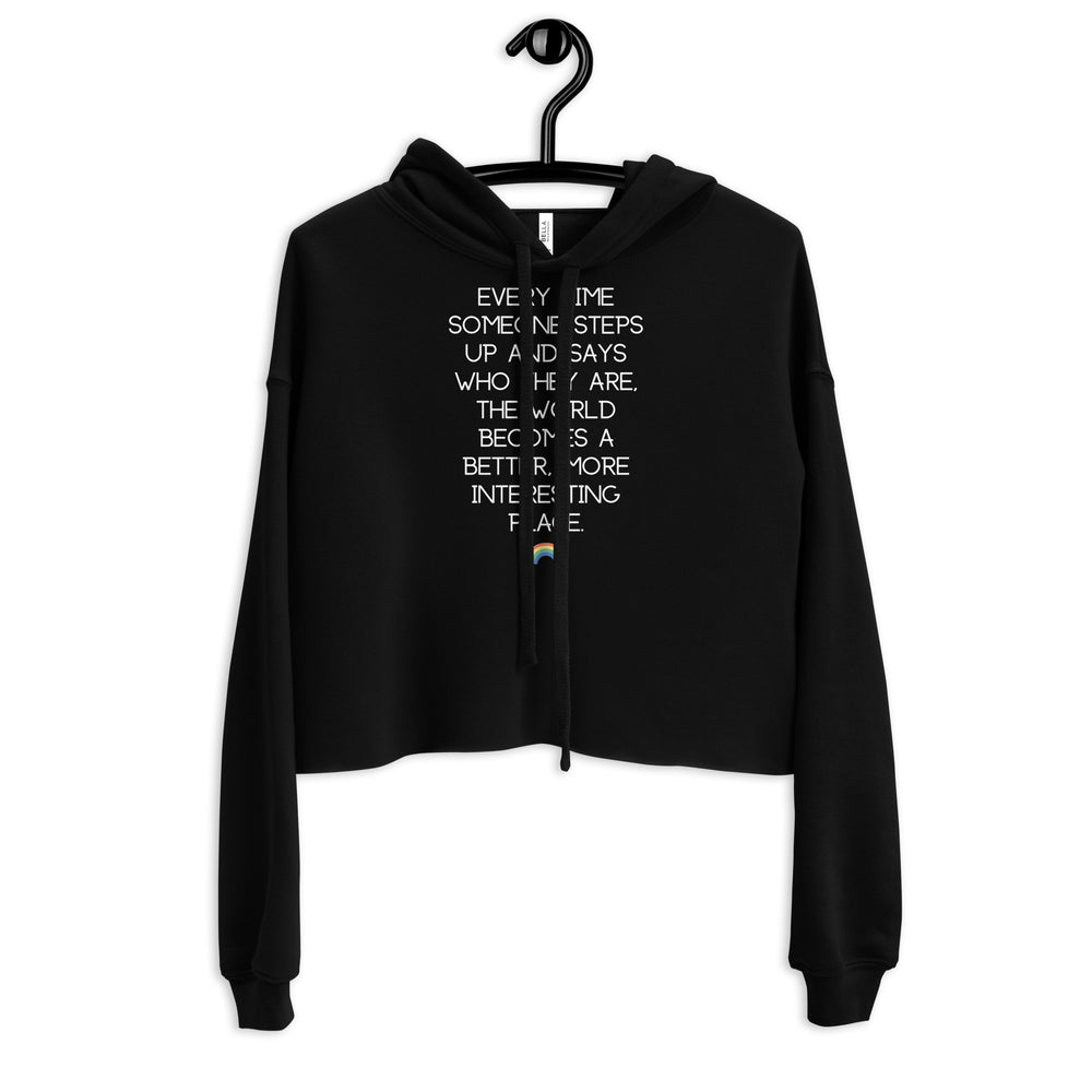 Front view of a black cropped hoodie on a hanger with white text and a rainbow accent