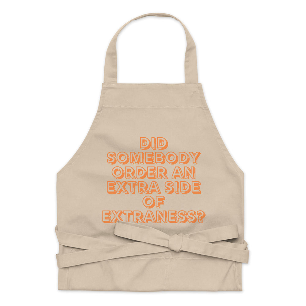 Front view of a beige apron with orange text reading “DID SOMEBODY ORDER AN EXTRA SIDE OF EXTRANESS?”