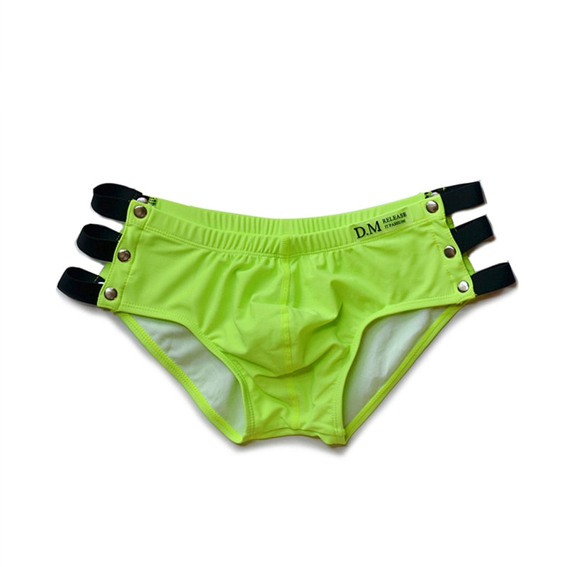 Neon green side-cutout swim briefs with black straps and snap details, shown flat