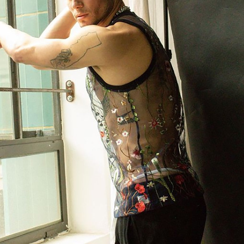 Model in a black sheer tank top embroidered with colorful flowers by a window
