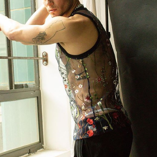Model in a black sheer tank top embroidered with colorful flowers by a window
