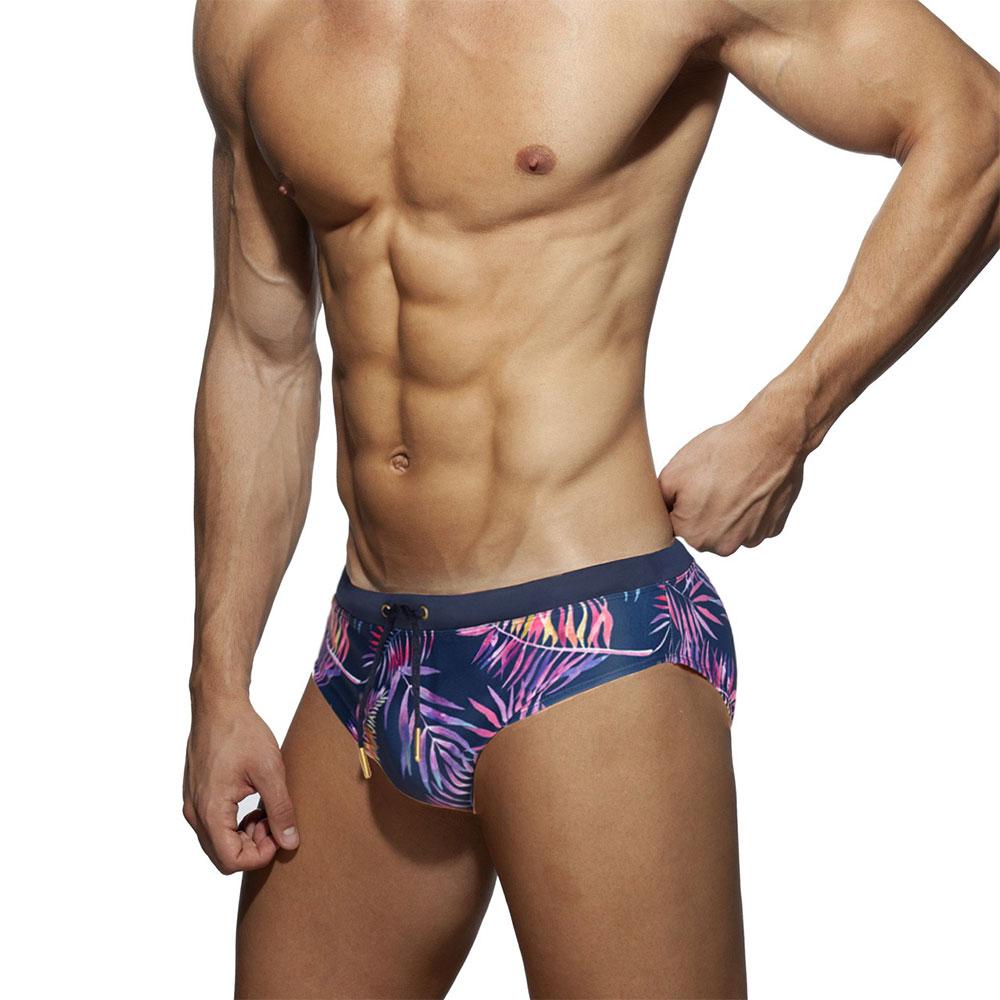Floral fern swim briefs with a dark navy base, pink and yellow tropical leaf print, and drawstring waist