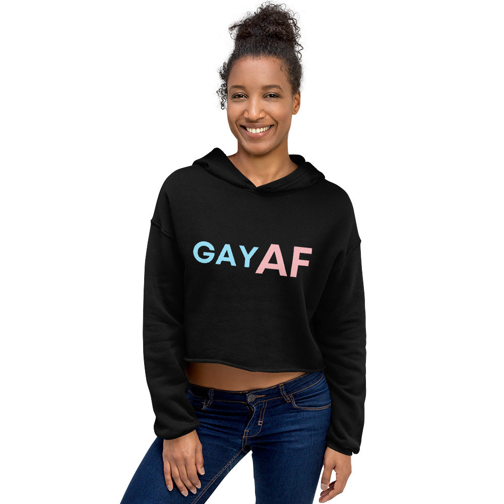 Front view of a smiling model wearing a black cropped hoodie reading “GAY AF” in blue and pink