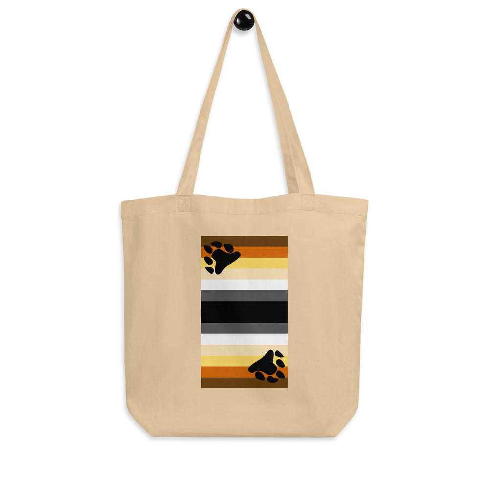 Front view of a beige tote bag with a bear pride flag and black paw prints