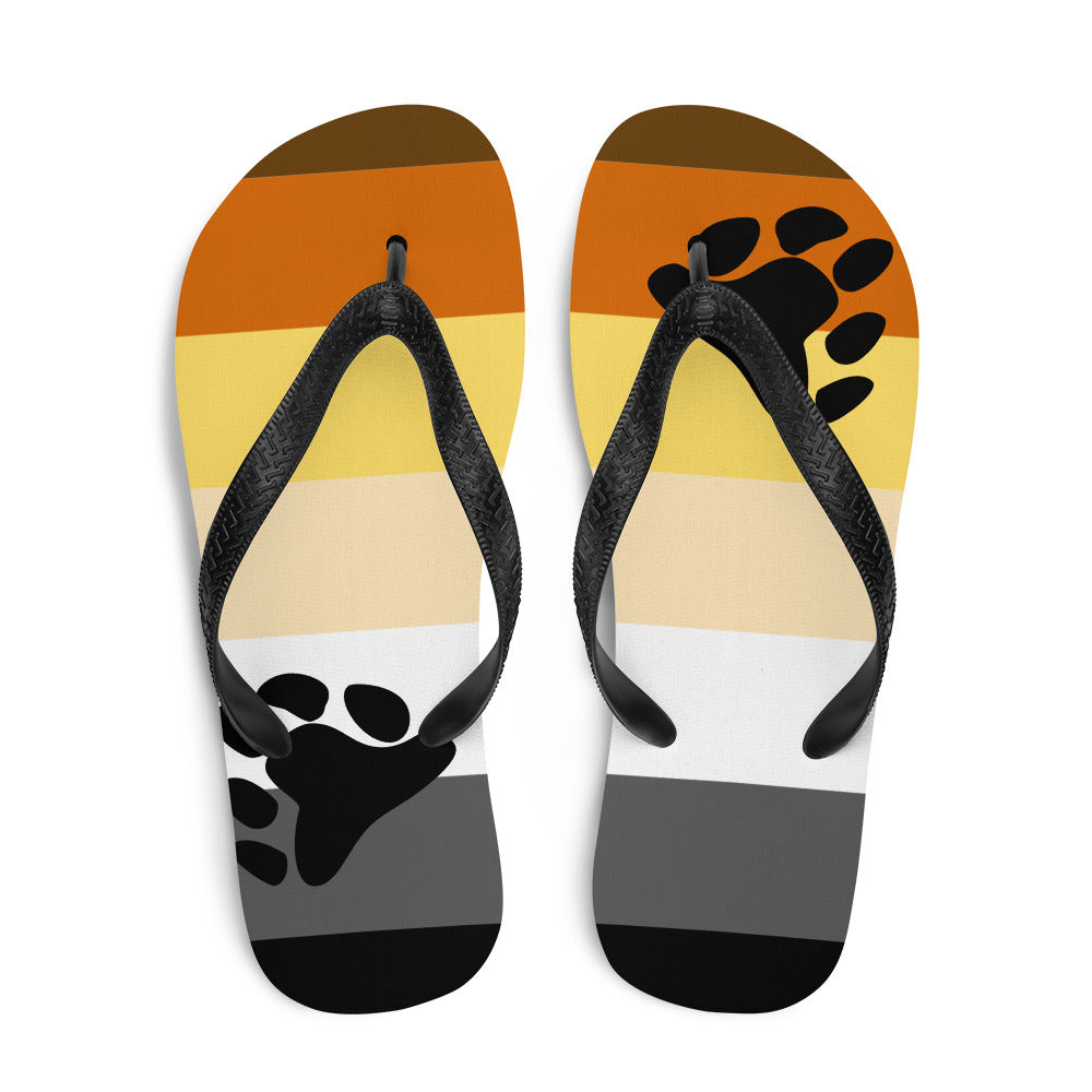 Pair of black-strap flip-flops with orange, yellow, cream, white, gray and black stripes and bear paw prints