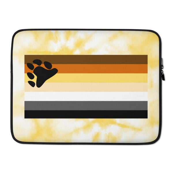 Gay Bear Pride laptop sleeve with brown, orange, yellow, and black stripes plus a bear paw sits on wood and leather in moody light.