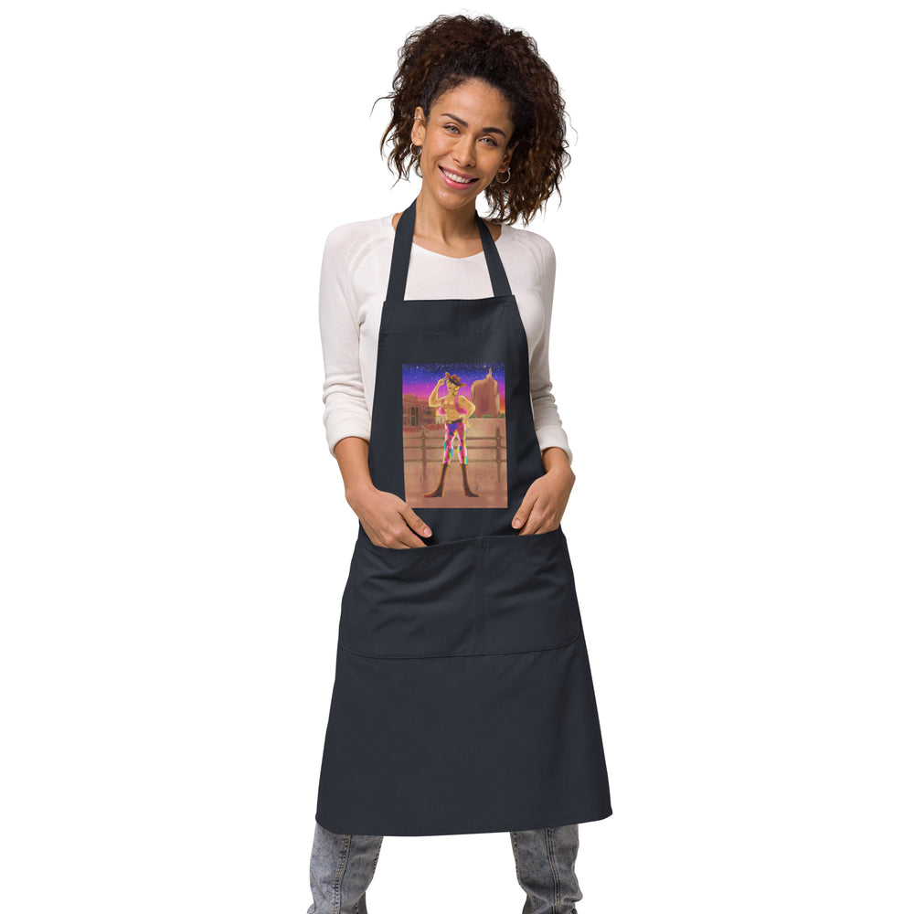 Front view of a smiling model wearing a black apron with a colorful cowboy-at-sunset graphic