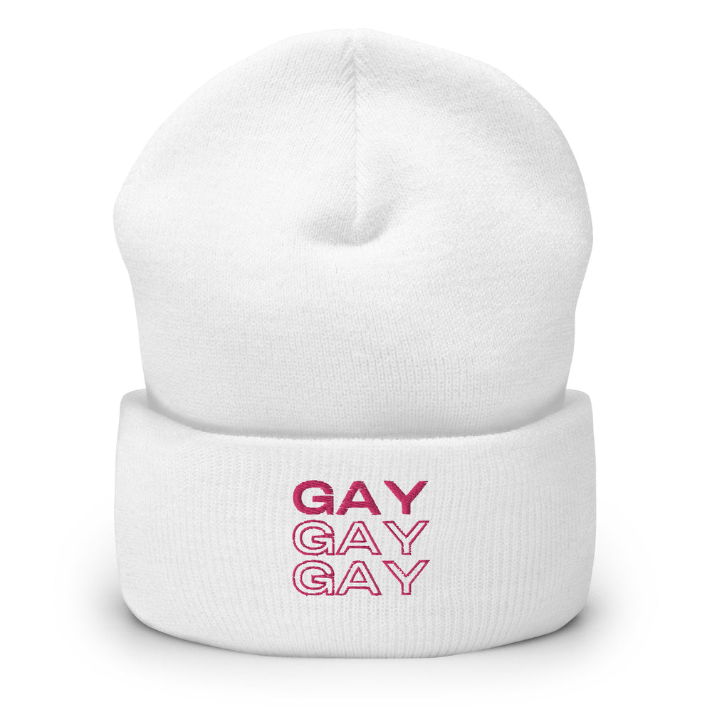 Front view of a white cuffed beanie with “GAY” printed three times in pink.