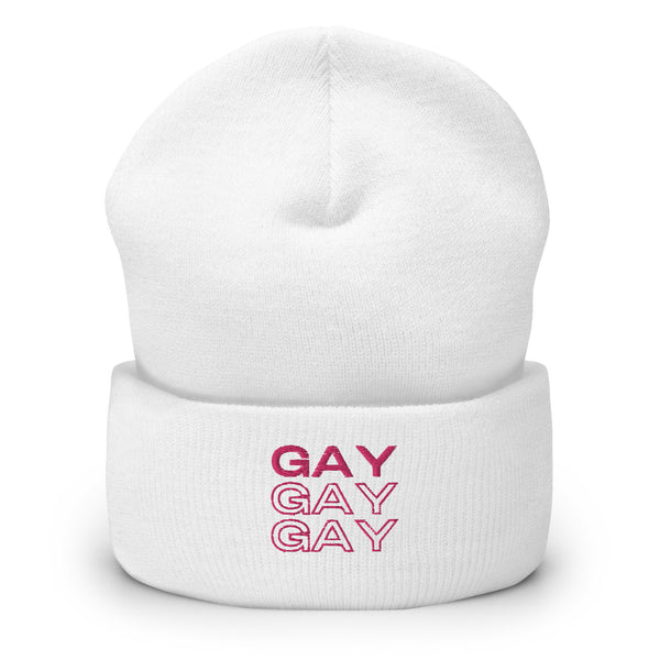Front view of a white cuffed beanie with “GAY” printed three times in pink.