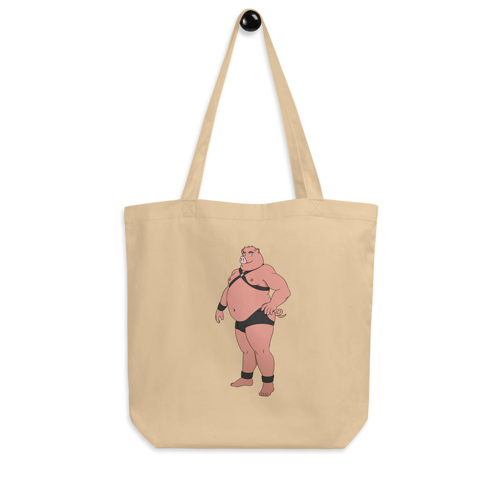 Natural canvas tote bag featuring a pink anthropomorphic pig in black briefs and harness