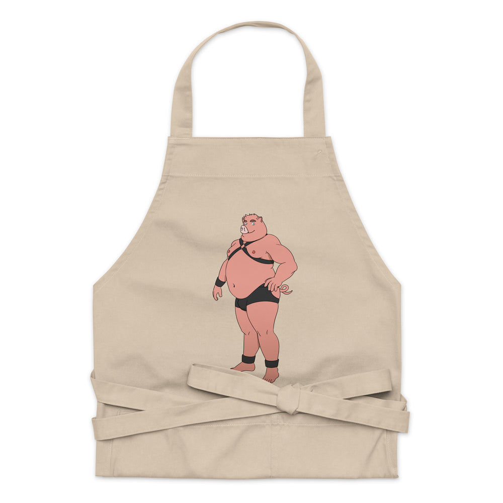 Front view of a beige apron featuring a cartoon pig in black harness gear and briefs