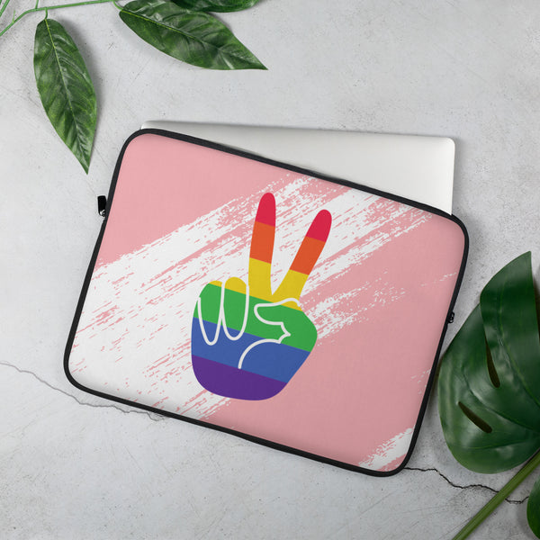 Pink laptop sleeve with a rainbow-striped peace-sign hand graphic, shown at an angle on a white surface