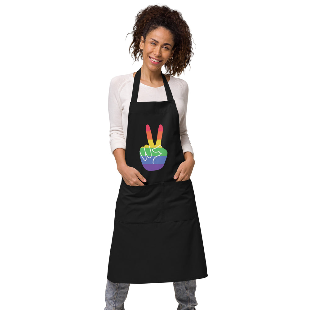 Front view of a model wearing a black apron with a rainbow peace-hand graphic